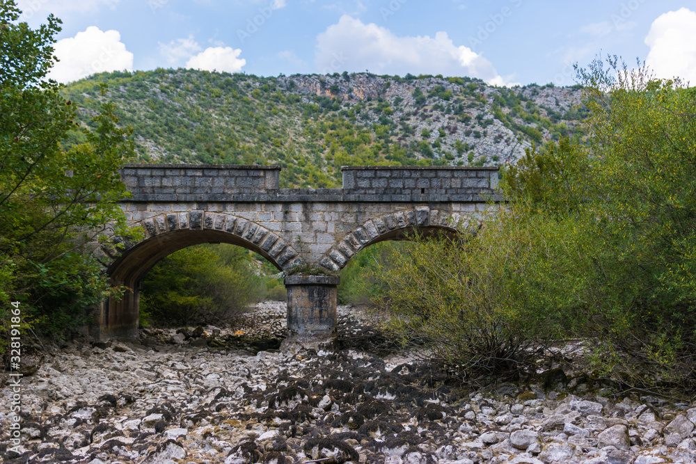 Fototapeta premium Old stone bridge and dry riverbed in hot summer. Knin in Croatia.