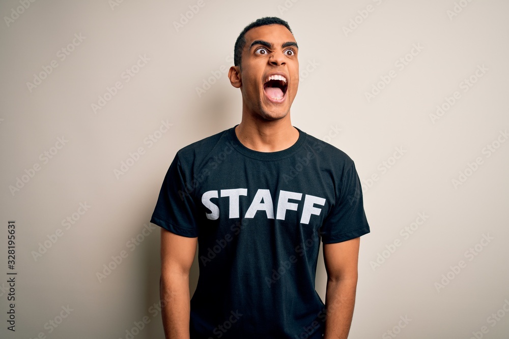Young handsome african american worker man wearing staff uniform over white background angry and mad screaming frustrated and furious, shouting with anger. Rage and aggressive concept. Young handsome african american worker man wearing staff uniform over white background angry and mad screaming frustrated and furious, shouting with anger. Rage and aggressive concept.