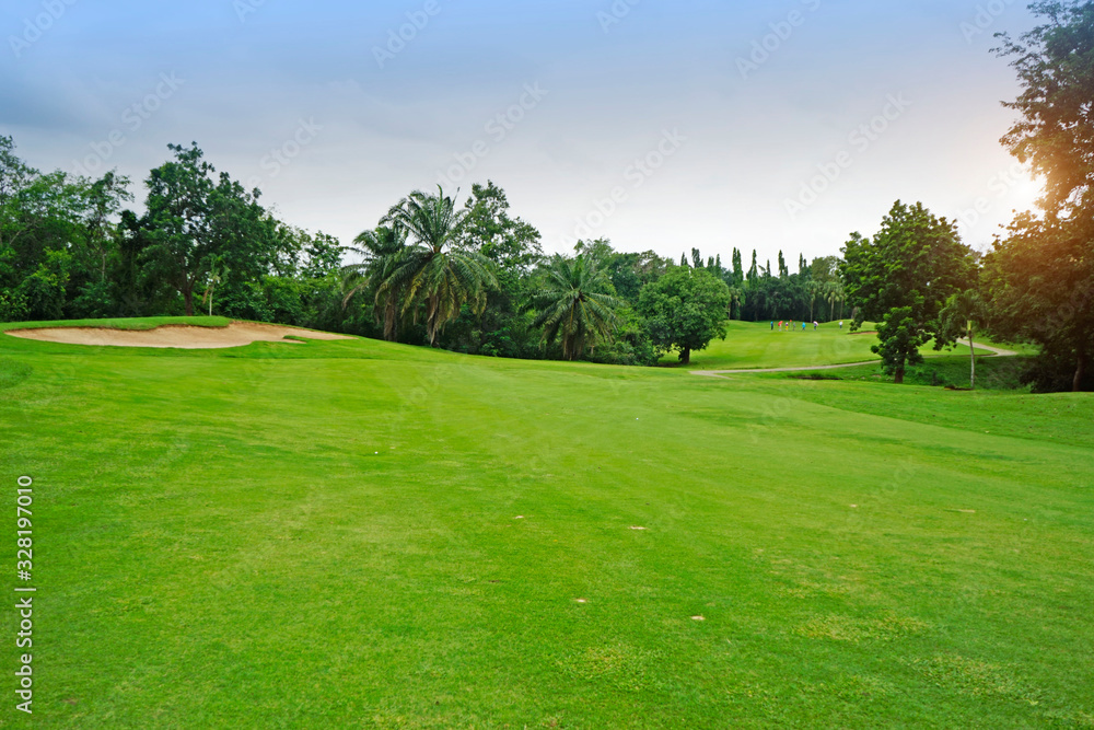 The evening golf course has sunlight shining down at golf course in Thailand