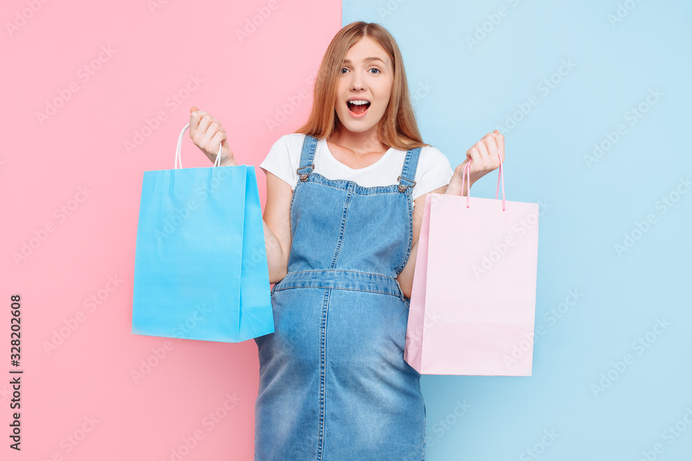 A pensive, confused pregnant woman holds a pink bag for a girl and a blue one for a boy. Choosing the child's gender A pensive, confused pregnant woman holds a pink bag for a girl and a blue one for a boy. Choosing the child's gender