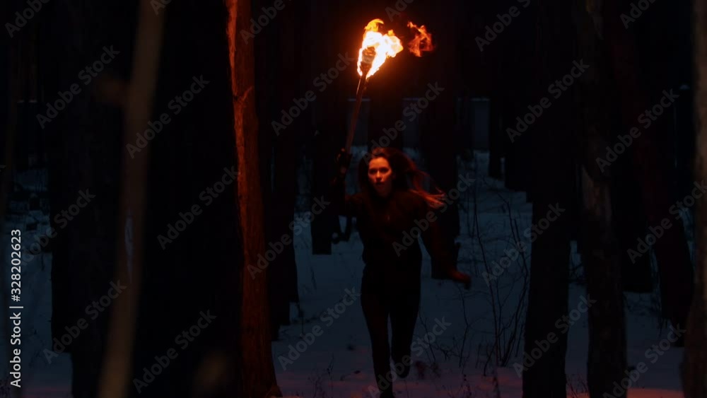 Young woman walking in the forest at night time holding a torch Young woman walking in the forest at night time holding a torch