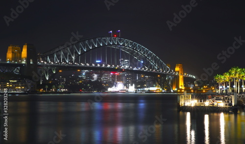 Sydney Harbour Bridge illuminating the harbour and circular quay with vibrant colourful lights at midnight in NSW Australia