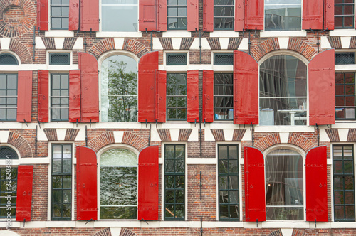 Photography Front view of vintage windows with red wooden shutters of traditional house