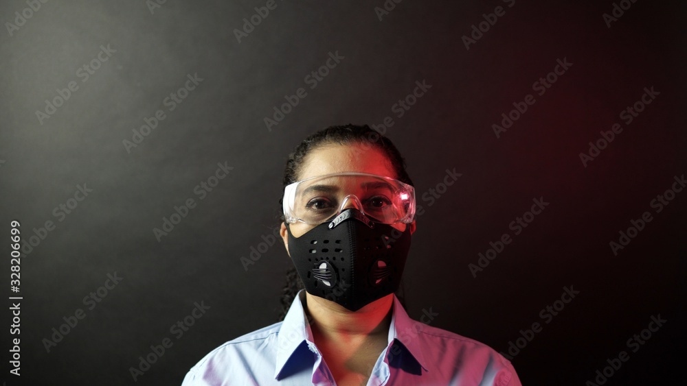 Woman in urban protective or medical mask with glasses, looking at the camera on black background. Coronavirus pathogen outbreak pandemic concept. Virus disease 2019-nCoV protection and prevention.
