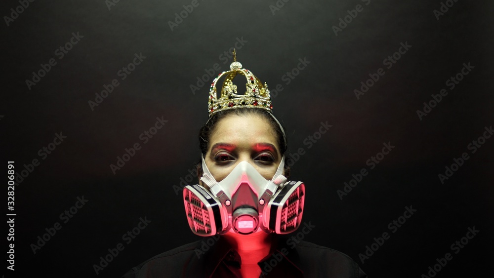 Woman in the heavy duty biohazard medical mask put the crown or corona on the head.  Personal forced home quarantine isolation from Coronavirus or covid 19 concept. Apocalypses and depression mood.