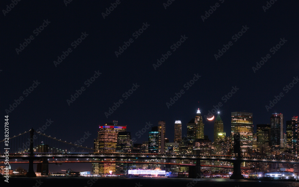 View of Downtown Manhattan with a crescent moon at night from the East River