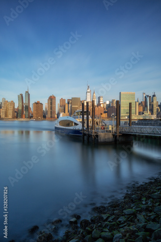 View on midtown manhattan from East river with ferry boarding   during sunrise with long exposure