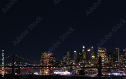 View of Downtown Manhattan with a crescent moon at night from the East River