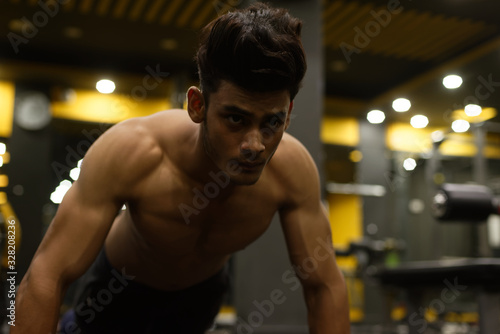 An young and handsome Indian Bengali brunette man with muscular body doing exercise in a multi gym. Fitness and Indian lifestyle.