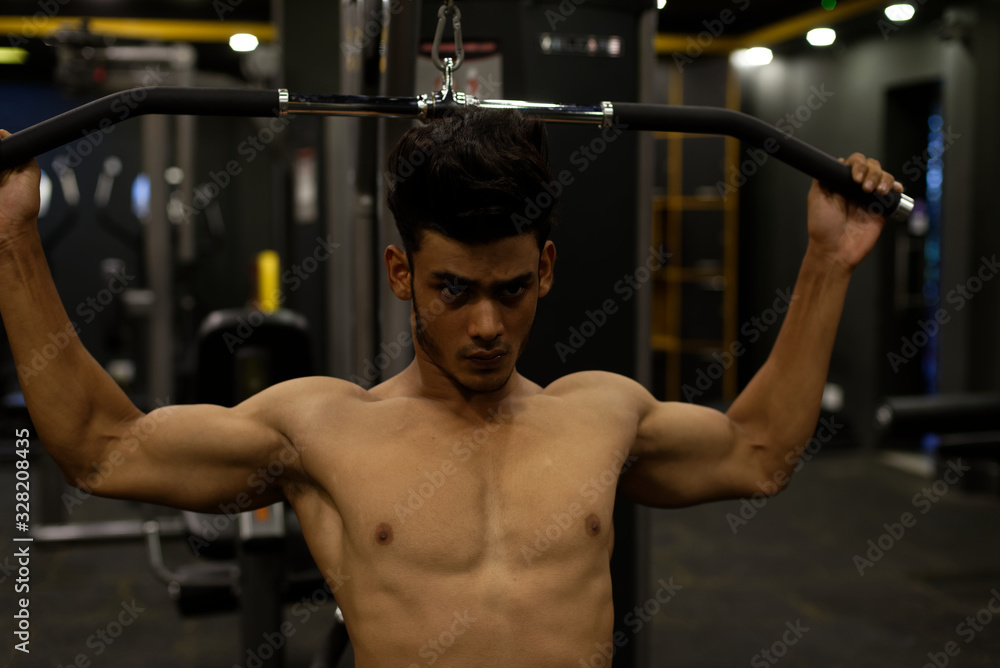 An young and handsome Indian Bengali brunette man with muscular body doing exercise in a multi gym. Fitness and Indian lifestyle. An young and handsome Indian Bengali brunette man with muscular body doing exercise in a multi gym. Fitness and Indian lifestyle.