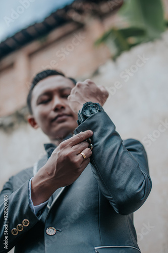 Selective focus of groom is standing with concrete wall background. Wedding concept.