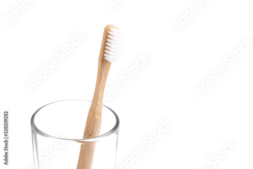 Bamboo toothbrush close-up in glass on white background. Eco friendly and zero waste concept photo.