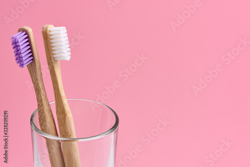 Two bamboo toothbrush close-up in glass on white background. Eco friendly and zero waste concept photo.