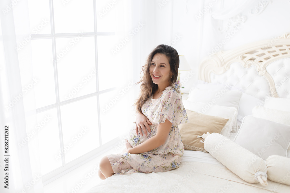 Pregnant Asian woman sitting on bed at home Pregnant Asian woman sitting on bed at home