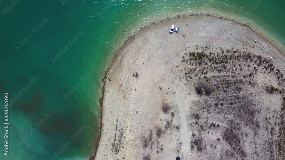 Aerial shot over a rv camped near a lake with turquoise water in the desert. Aerial shot over a rv camped near a lake with turquoise water in the desert.