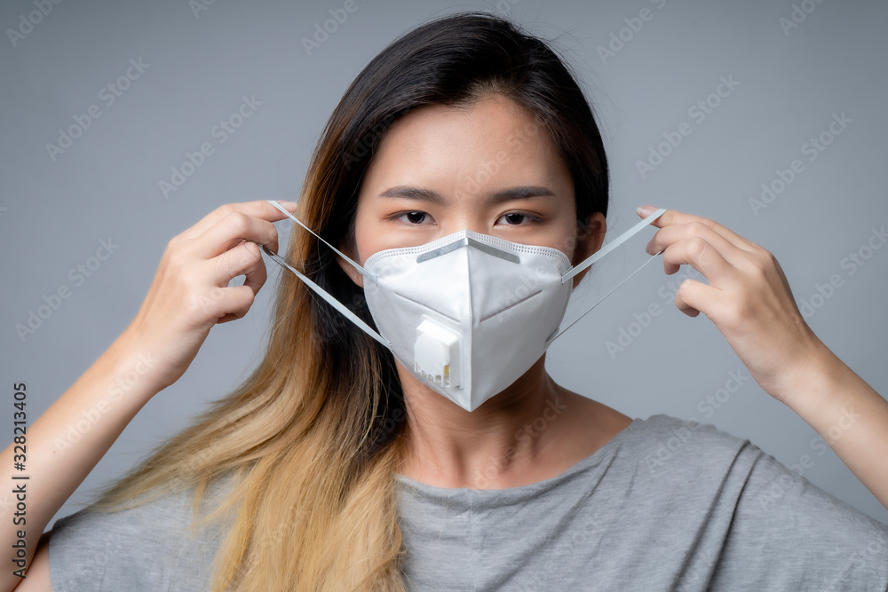 Young woman wearing surgical mask, studio shot