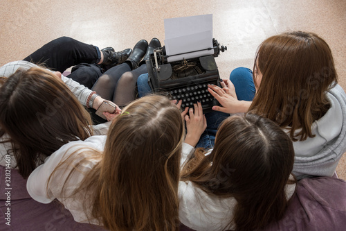 Young girls students. The first acquaintance with an old typewriter. Typewriter or laptop. What to choose?