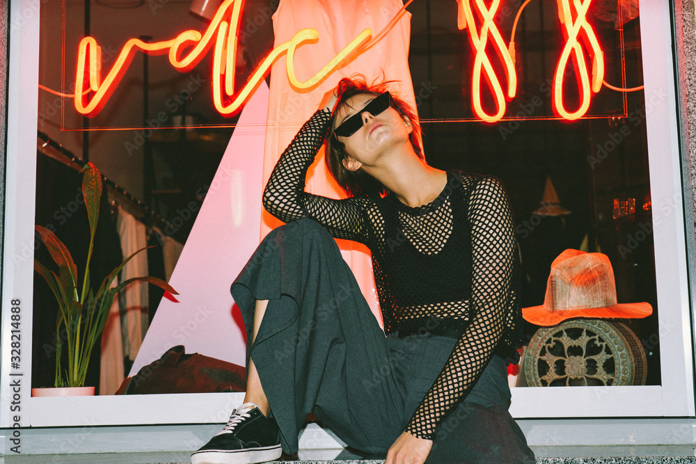 © insta_photos - Pretty young girl hipster teen model advertise trendy dark clothing sunglasses sit pose over big shop window led lighting showcase background high fashion urban lifestyle night life concept copyspace. © insta_photos - Pretty young girl hipster teen model advertise trendy dark clothing sunglasses sit pose over big shop window led lighting showcase background high fashion urban lifestyle night life concept copyspace.