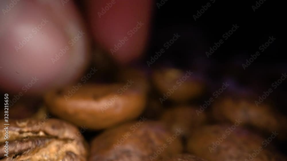 Macro shot of roasted Coffee beans being picked up by male fingers in background. Aroma of coffee beans. Macro shot of roasted Coffee beans being picked up by male fingers in background. Aroma of coffee beans.