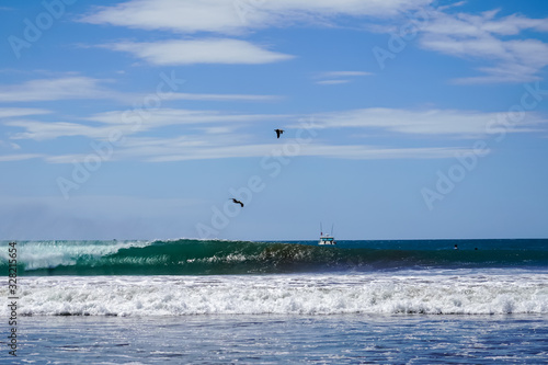 Beautiful aerial view of surfers surfing in Naranjo Beach 