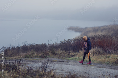 Sad teenager girl with  teddy bear on country road by foggy  lake.  Concept of adolescence and adolescent problems.