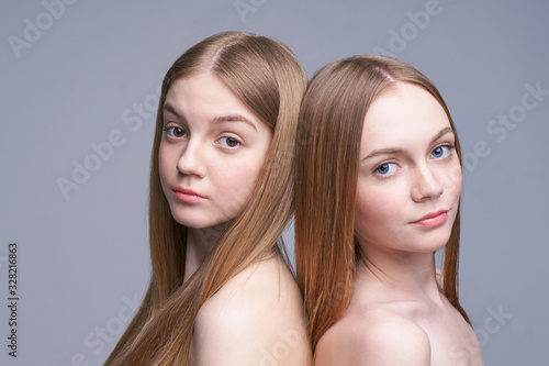 Two young caucasian beautiful girl portrait. Serious model looking at camera. Pretty woman at studio. No make up