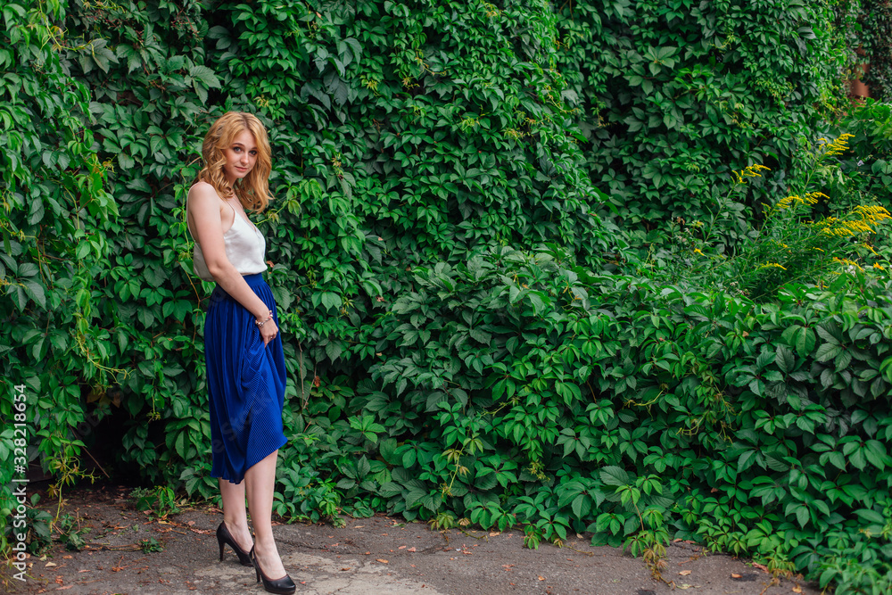 Portrait of a young beautiful woman, standing next to the wall of wild grape leaves. Portrait of a young beautiful woman, standing next to the wall of wild grape leaves.