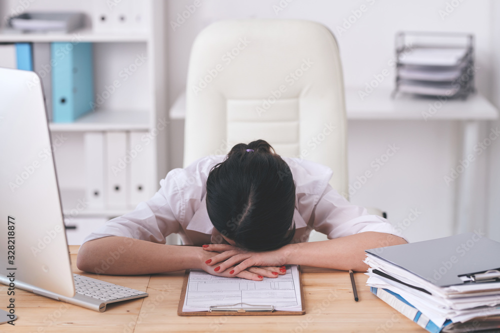 Puzzled brunette woman tired from work lying on table with application form while processing requests Puzzled brunette woman tired from work lying on table with application form while processing requests