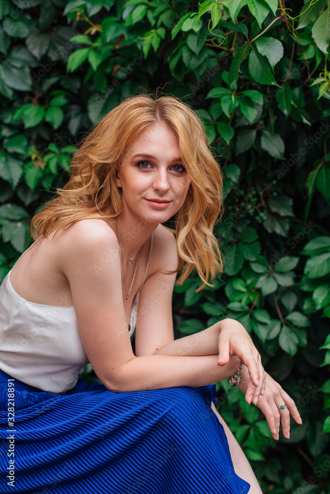 Portrait of a young beautiful woman, sitting next to the wall of wild grape leaves. Portrait of a young beautiful woman, sitting next to the wall of wild grape leaves.