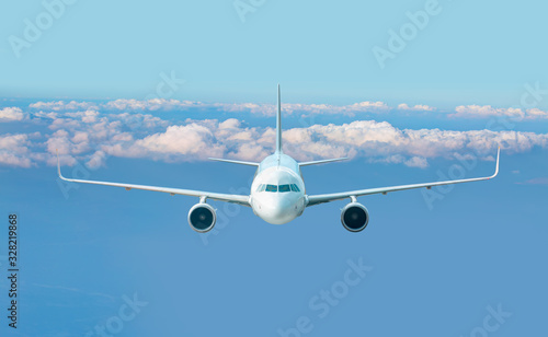An airplane is flying over low clouds with blue sky