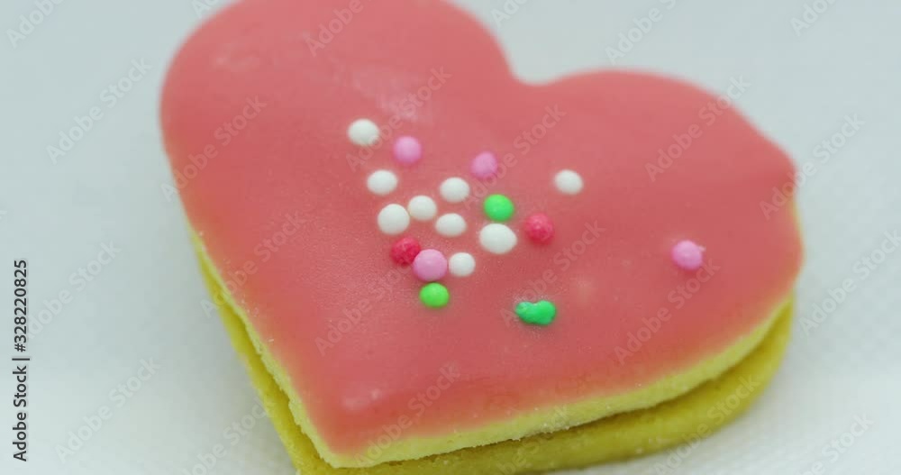 Zoom in close-up macro view of the center of a Christmas candy in the form of a pink heart decorated with colorful balls and its corpus in close up shot in slow motion capture. Zoom in close-up macro view of the center of a Christmas candy in the form of a pink heart decorated with colorful balls and its corpus in close up shot in slow motion capture.