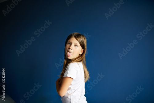 child girl offended, shows tongue on deep blue