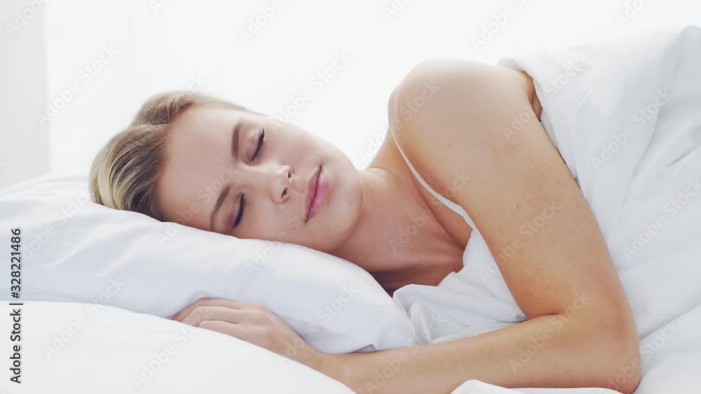Young woman lying in the bed. Beautiful blond sleeping girl. Morning in the bedroom. Health and rest concept. Young woman lying in the bed. Beautiful blond sleeping girl. Morning in the bedroom. Health and rest concept.