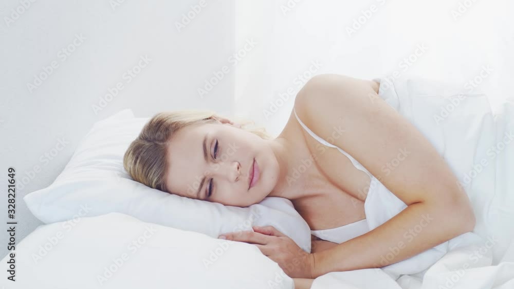 Young woman lying in the bed. Beautiful blond sleeping girl. Morning in the bedroom. Health and rest concept. Young woman lying in the bed. Beautiful blond sleeping girl. Morning in the bedroom. Health and rest concept.