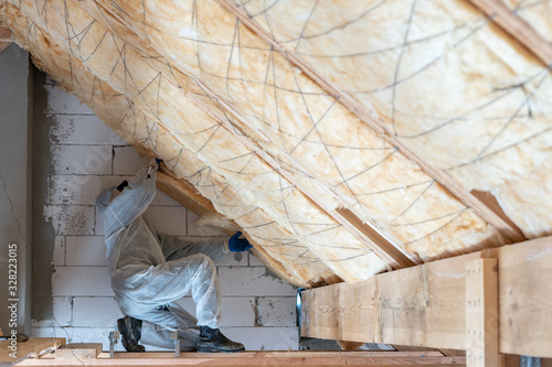 Worker man in overalls working with rockwool insulation material photo