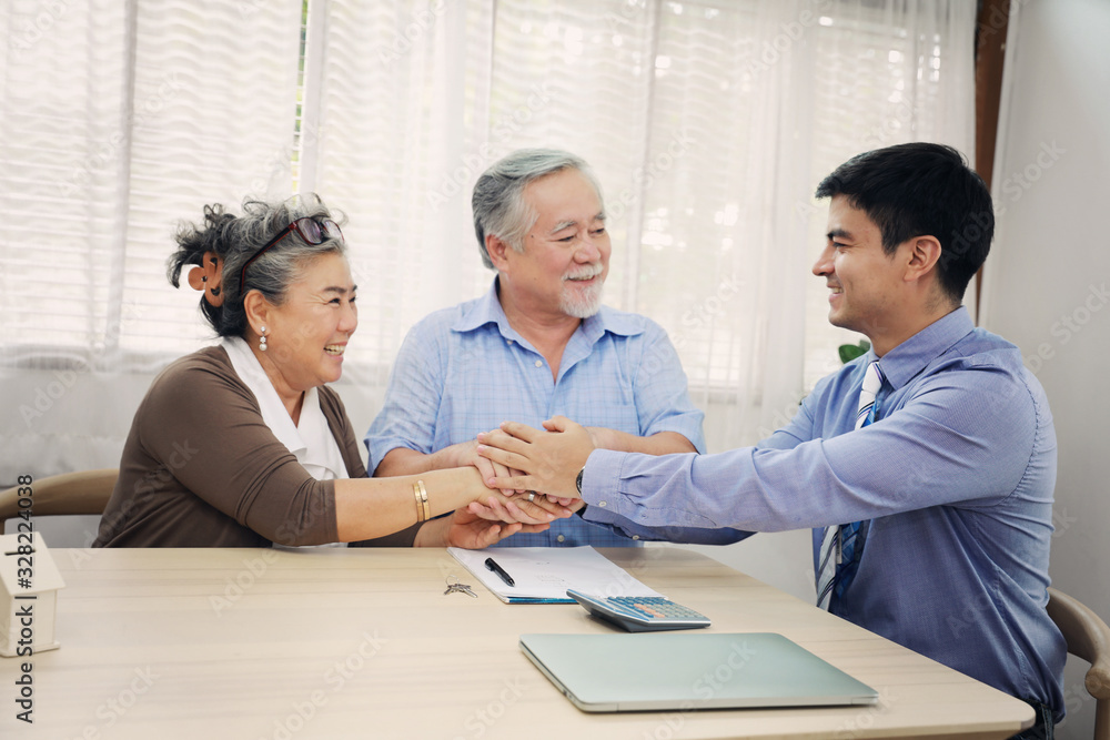 Asian couple grandparent are happy with insurance agency manager after deal the agreement successful, financial planner presenting and Closing the sale of real estate Asian couple grandparent are happy with insurance agency manager after deal the agreement successful, financial planner presenting and Closing the sale of real estate