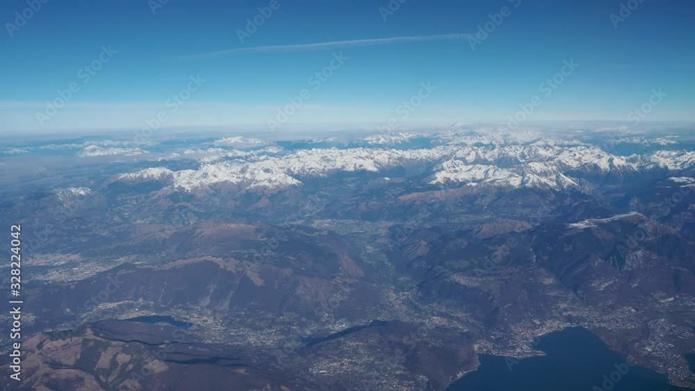 Flying over the European Alps during spring season. Aerial view from the airplane window Flying over the European Alps during spring season. Aerial view from the airplane window