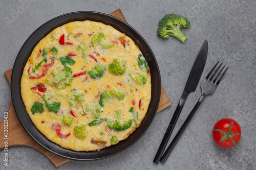 Frittata with fresh vegetables. Omelette with broccoli, paprika, tomato and herbs. Top view. 