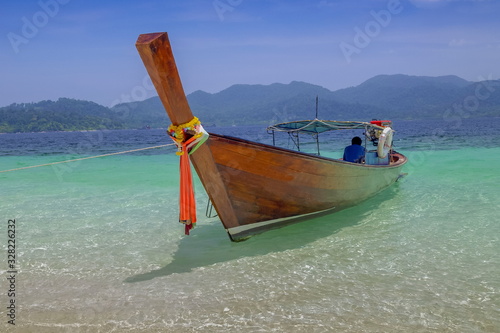 view seaside of a long-tail boat floating in blue-green sea and blue sky background, Monkey island, long-tail boat trip from Lipe island, Satun, southern Thailand. © Yuttana Joe