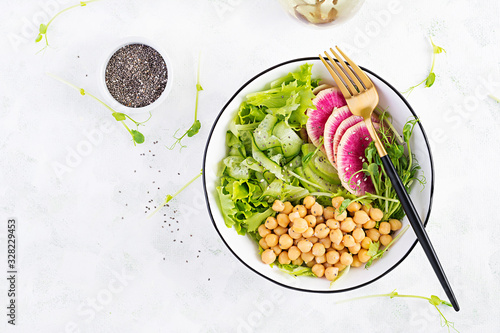 Trendy salad. Vegan Buddha bowl with chickpeas, watermelon radish, cucumber and peas sprouts. Healthy balanced eating. Top view, overhead, flat lay