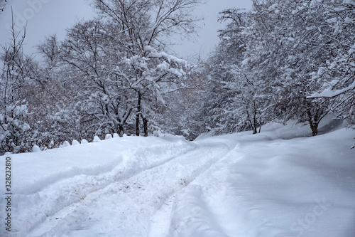 Mountain winter road in snowfall. Beautiful winter landscape. Snow covered dangerous road, blizzard in mountains. © Adil