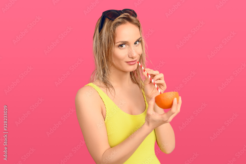 Woman drinking through a straw from an orange Woman drinking through a straw from an orange
