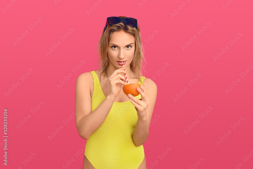 Woman drinking through a straw from an orange Woman drinking through a straw from an orange