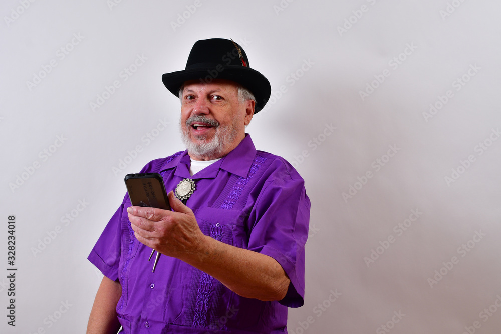 Smiling old man looking at his cellphone .Dapper old man smiling at the picture in the smartphone.Sharp dressed senior man smiling and looking at his mobile phone.. Smiling old man looking at his cellphone .Dapper old man smiling at the picture in the smartphone.Sharp dressed senior man smiling and looking at his mobile phone..