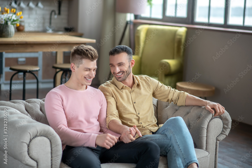 Two young men sitting on the sofa and smiling