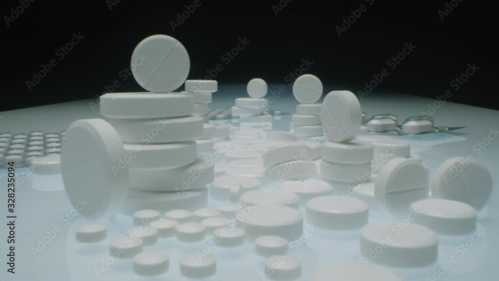 Zoom in shot of stacks of white round tablets and blister packs with medicine pills on table in studio Zoom in shot of stacks of white round tablets and blister packs with medicine pills on table in studio