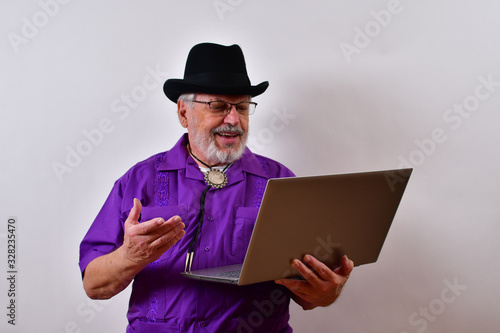 Smiling man using his laptop computer..Well dressed old man using his laptop computer.