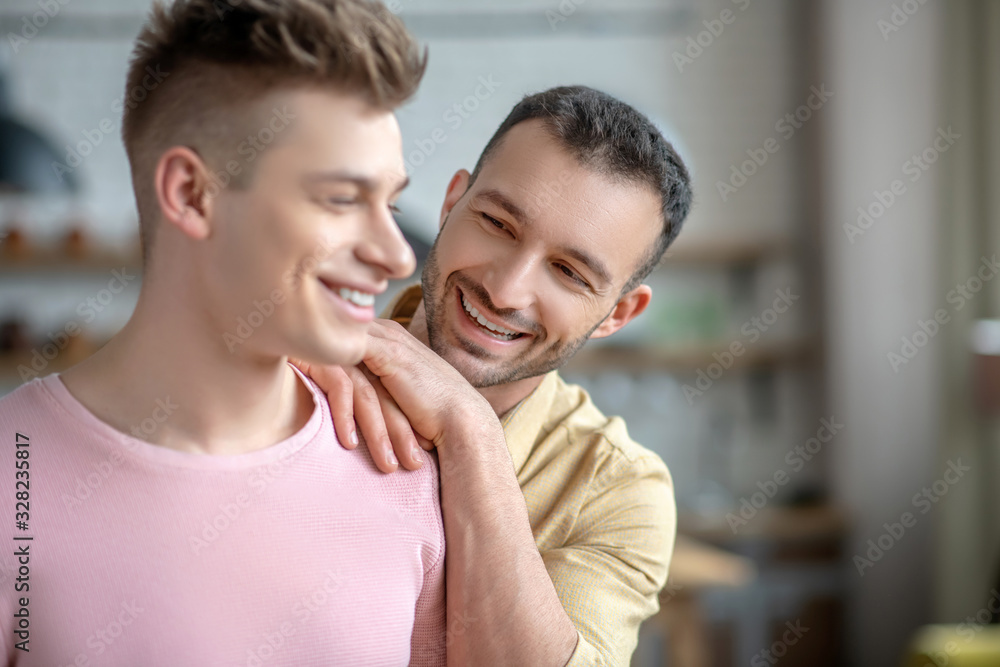 Dark-haired man in orange shirt putting hands on his partners shoulder Dark-haired man in orange shirt putting hands on his partners shoulder