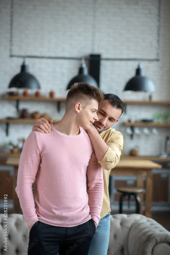 Fototapeta premium Dark-haired man in orange shirt hugging his partner