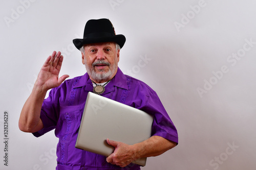 Sharp dressed senior man holding his laptop computer and waving..